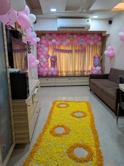 The full view of a living room decorated for a baby's welcome, with the flower runner leading towards a backdrop of pink balloons.