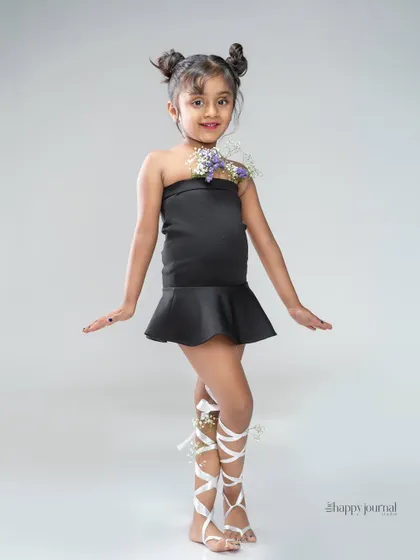 A full-body shot from a creative kids' portrait session. The styling with flowers and ribbons adds a touch of whimsy, while the confident pose is perfect for a young performer's portfolio.