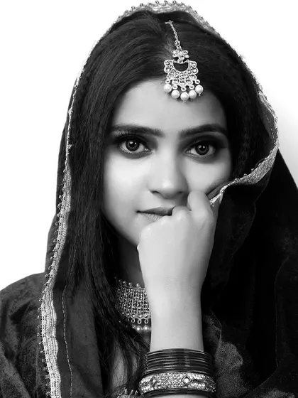 This striking black and white portrait captures a model in traditional attire. The focus on her eyes and the framing with the dupatta create a powerful and emotive image, ideal for a bridal or ethnic beauty portfolio.
