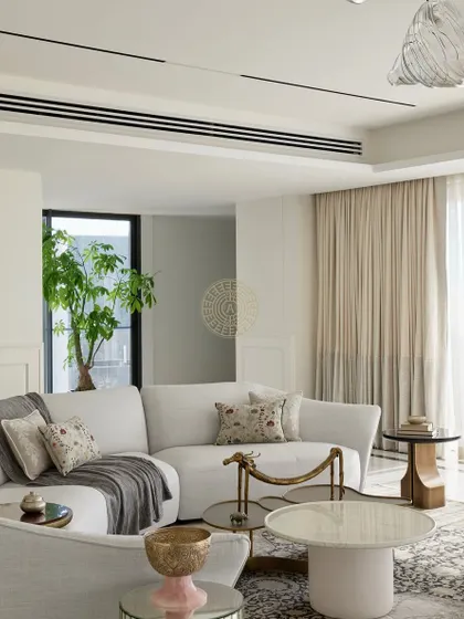 The curved white sofa provides a soft, inviting anchor in this luxurious living room. We layered different textures, from the plush rug to the metallic side tables, to create a space that feels both sophisticated and comfortable.