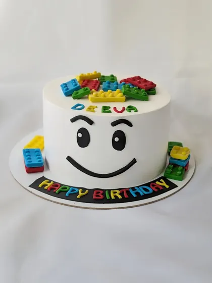 Building a happy birthday with this simple and fun Lego cake. The design features the iconic Lego face and colorful, edible Lego blocks.