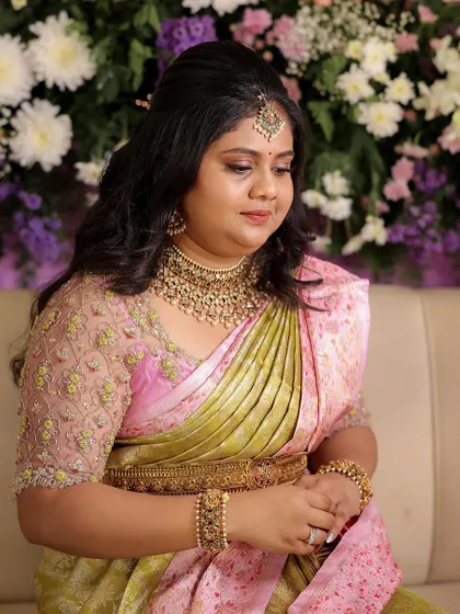 This client looks like a doll in her pastel pink and green saree for her engagement. The custom-designed blouse with intricate embroidery adds a touch of glamour to her look.