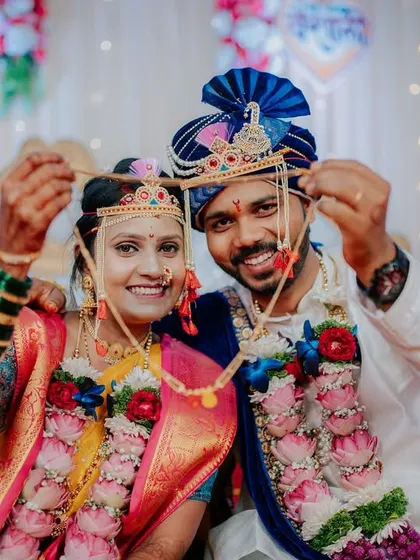 A playful and happy portrait of the couple showing off their traditional headwear (Mundavalya).