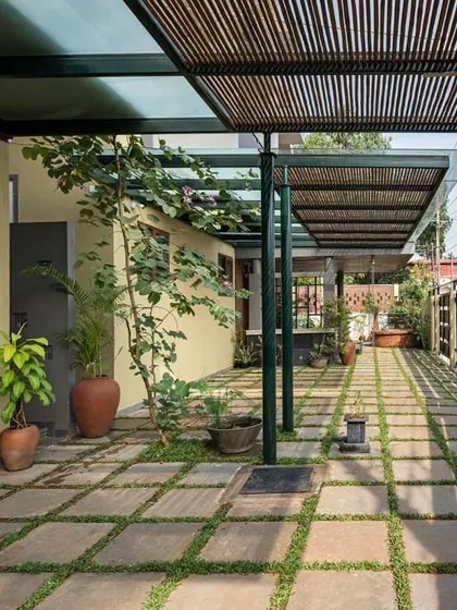 A repeat view of the entrance pathway, emphasizing its role as a multi-functional space for parking, play, or gatherings. The design thoughtfully combines landscape, shelter, and utility.