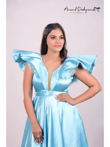 A close-up of the sky-blue satin gown, showing the detail of the ruffled shoulders and deep neckline.