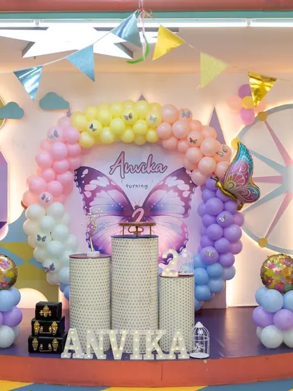 An elaborate butterfly-themed stage for a second birthday, with a pastel color palette and large butterfly wing decorations. We pay close attention to capturing the scale and detail of your event's design.