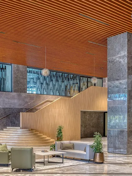 The grand lobby of Aurobindo Orbit, showcasing a mix of marble, wood battens on the ceiling, and contemporary furniture. The space was designed to have the sophistication of a hospitality project, creating a strong identity for the building.