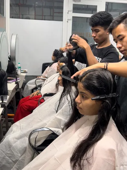 A busy day in the classroom, with students practicing haircuts on live models under the supervision of our expert trainers.