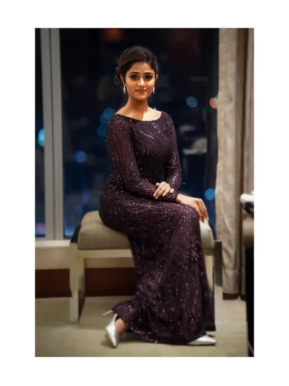 A slightly different angle of the full-length seated pose, this image shows the elegant drape of the gown. It’s a great shot for showcasing evening wear in a sophisticated setting.