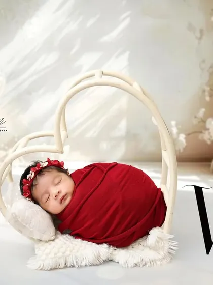 Wrapped in love. This beautiful shot features a newborn in a vibrant red swaddle, nestled inside a heart-shaped prop for a simple yet powerful statement.