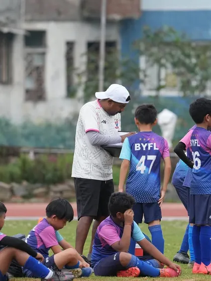 A coach reviews his notes while the team rests on the sidelines. Meticulous planning and guidance are part of our coaching philosophy.