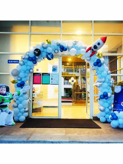 A grand entrance for a space-themed party. A large balloon arch with a rocket and a Buzz Lightyear cutout welcomes guests to an exciting celebration.