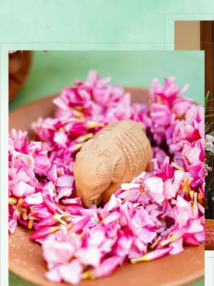 A detail shot showing a terracotta elephant figurine nestled in a bed of pink flower petals. It's these small, thoughtful touches that bring a theme to life.
