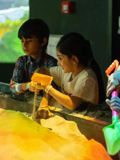 Friends working together in the illusion sand pit, where they can build mountains and create oceans with augmented reality.