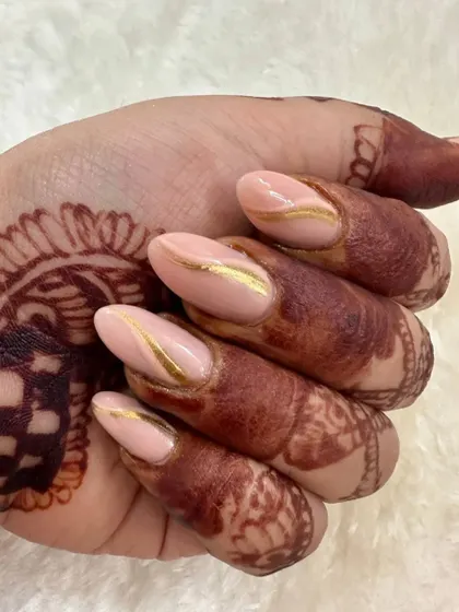 A close-up showing the delicate gold chrome wave on these pastel peach bridal nails, a beautiful detail against the henna.