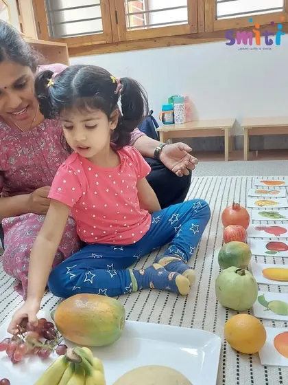 A child matches real fruits to their corresponding picture cards before making a salad. This language activity enriches vocabulary and classification skills in a tangible way.