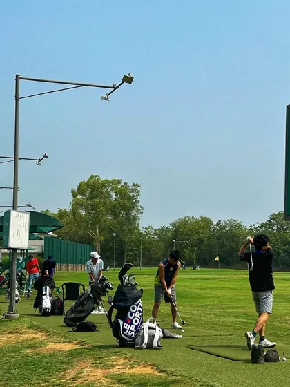A view of the range with our branding visible, showing golfers practicing near a Hamoni sign.
