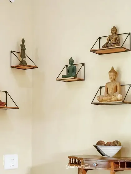 A gallery wall featuring a collection of Buddha statues on minimalist shelves. This serene and spiritual corner at Villa Magnolia, Coorg, creates a peaceful and contemplative atmosphere.