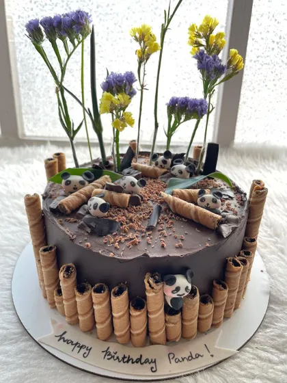 A chocolate cake for a panda lover! The design features little pandas in a bamboo forest made of chocolate wafer rolls.