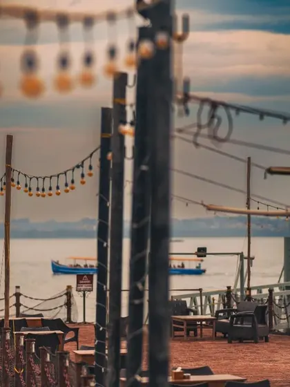 A wide-angle view of a couple on a pier, framed by string lights. This shot captures the beautiful ambiance of a seaside location and the feeling of a private, romantic moment.