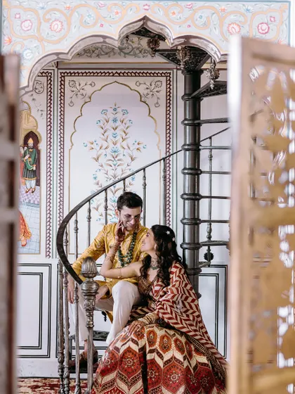 A romantic moment on a spiral staircase at Anantara Jaipur, capturing the couple in a quiet embrace during their haldi event.