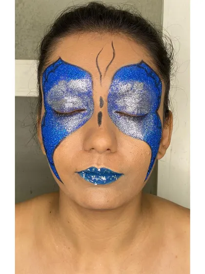 With eyes closed, you can see the full effect of the glitter butterfly wings. This demonstrates the complete artistry involved in creating symmetrical and impactful editorial makeup.