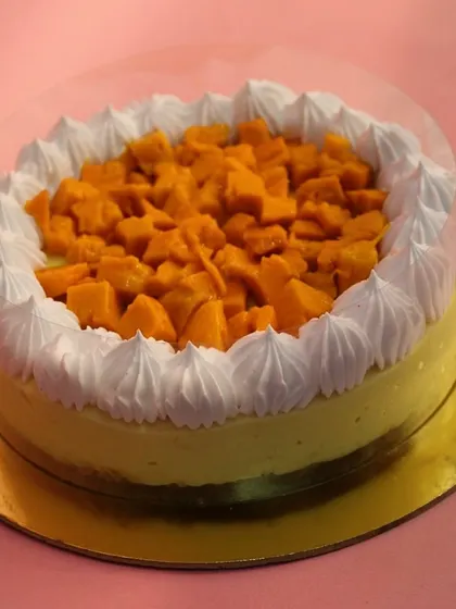 A beautiful half-kilogram Mango Cheesecake, generously topped with fresh mango pieces and ready for a celebration.