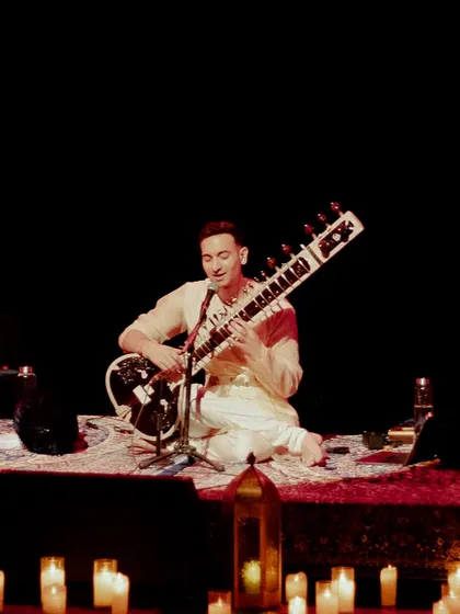 Performing with a tabla player in a classic, intimate duet format, surrounded by lanterns and candles.