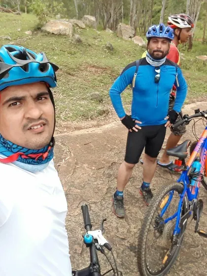 A selfie taken mid-ride, with fellow cyclists and their bikes in the background on a rocky trail.