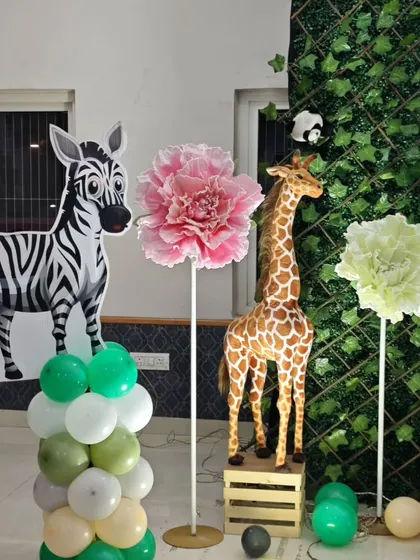 A side view of the decor for Shivansh's safari party, showing a zebra cutout and large paper flowers, adding a touch of elegance to the wild theme.