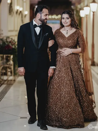 The couple walks arm-in-arm through a beautifully lit corridor. This shot captures the style and grace of their engagement celebration.