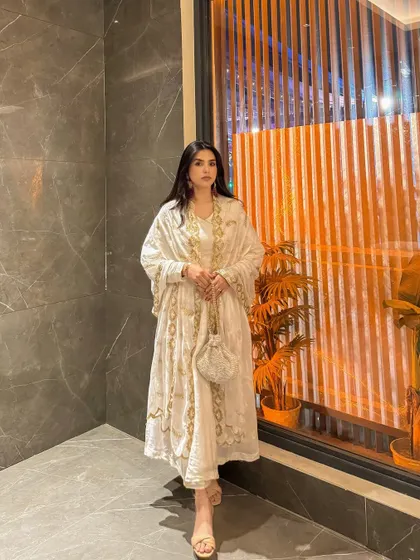 A full-length shot of the white Anarkali, showing the beautiful drape and intricate gold embroidery.