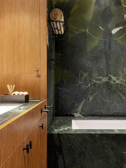 The bathroom adjoining the photographer's bedroom features a dramatic avocado marble. The deep green stone, with its natural veining, is paired with fluted wood to continue the home's material theme.