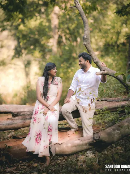 A serene portrait of a couple sitting on a log in a forest, creating a rustic and natural feel.
