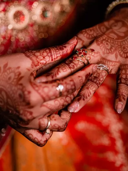 A close-up of the bride's hands, showcasing the intricate henna design and her beautiful wedding rings.