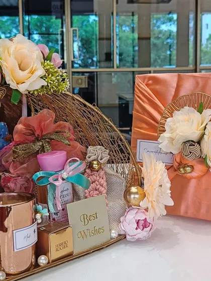 An elegant wedding hamper for a friend's special day. The gift includes a golden wire basket filled with curated items like a scented candle and Ferrero Rocher, paired with a Furoshiki-wrapped present.