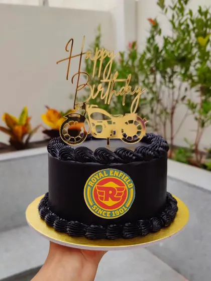 A cake for a Royal Enfield lover. The all-black buttercream cake is decorated with the brand's logo and a gold motorcycle topper.