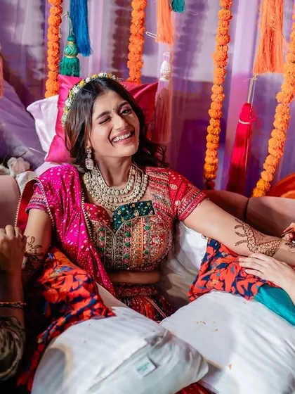 A happy, winking portrait of the bride enjoying her Mehendi ceremony.