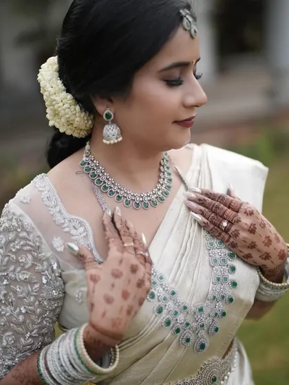 A close-up of the bride's hands, adorned with henna and beautiful jewelry, against her silver-work blouse.