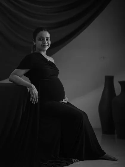 A graceful seated portrait in black and white. Removing the color allows the focus to be on the mother's serene expression and the classic lines of her pose.