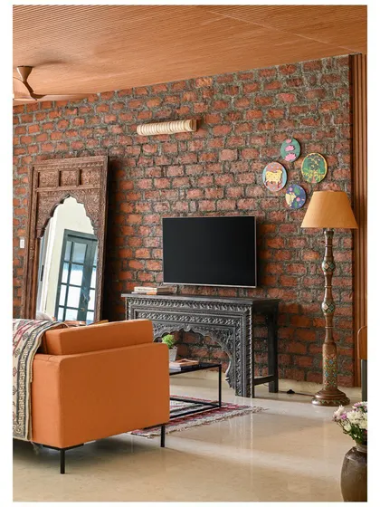 This 4BHK apartment in Goa was designed to blend traditional craftsmanship with modern living. The family lounge features an exposed brick wall, a carved console, and a large arched mirror to create an eclectic, inviting feel.