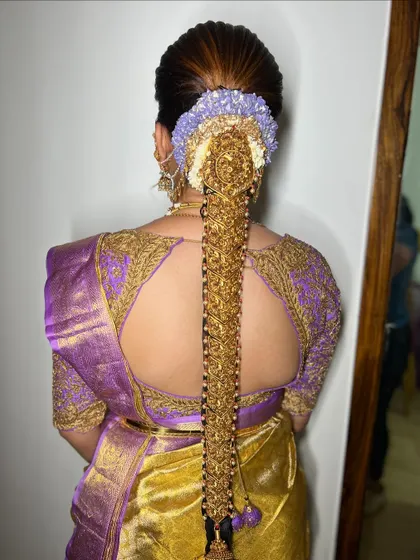 Another angle of the magnificent gold-adorned bridal braid. The intricate details of the jewellery and the richness of the silk saree make this a truly memorable bridal style.