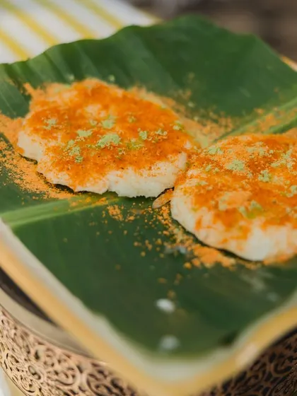 Tatte Idli, a popular dish from Karnataka, is known for its large, plate-sized shape and incredibly soft texture. I serve it on a traditional banana leaf, topped with a generous dusting of spicy podi.