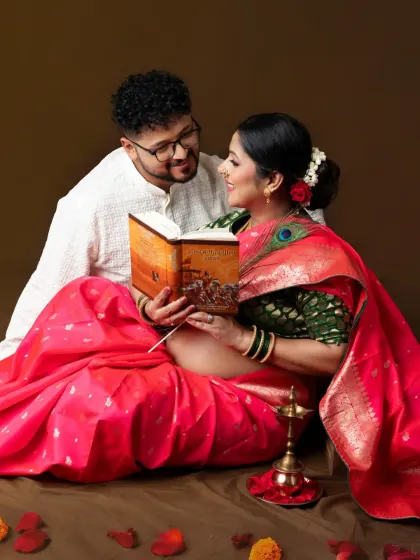 A sweet, shared moment. The couple reads a book together, a lovely way to symbolize the stories and values they will pass on to their child.