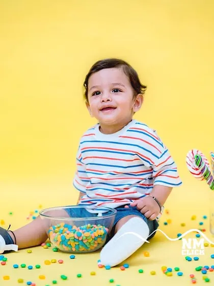 A minimalist studio session with a pop of color. The bright yellow background and colorful candies make for a fun and modern toddler portrait.
