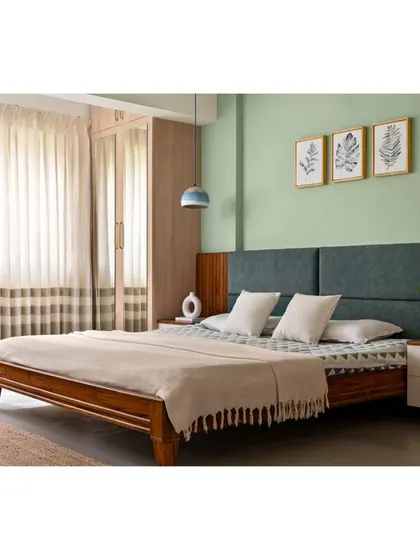 The guest bedroom transformation, where the balcony was also brought in to create more space. The room features a built-in teak wood bed with a forest green headboard against a pastel green wall.