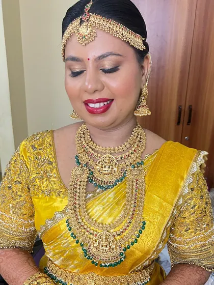 A happy bride on her wedding day. The bright yellow saree is perfectly complemented by a bold red lip and shimmering gold eyeshadow.