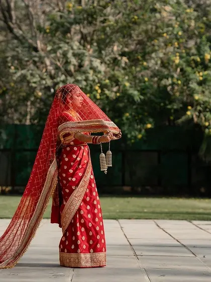 A bride in her red saree, veiled and ready for her ceremony. This traditional shot is full of anticipation and cultural significance.