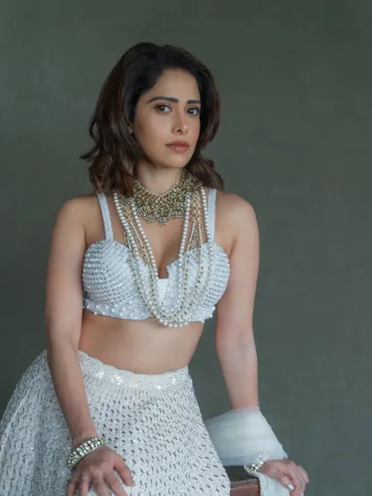 A close-up on the pearl-encrusted blouse of this white lehenga. The layered necklaces add a touch of royalty to this modern wedding outfit.