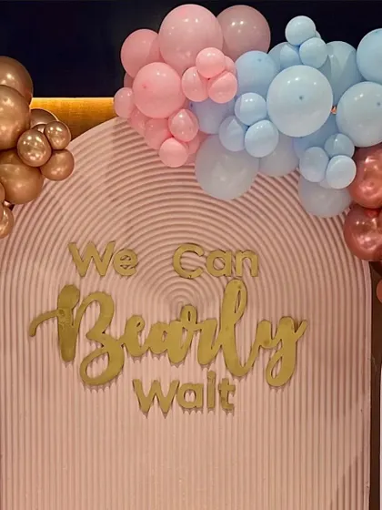 A "We Can Bearly Wait" baby shower backdrop. This close-up shows the 3D lettering and the pastel pink and blue balloon arrangement.